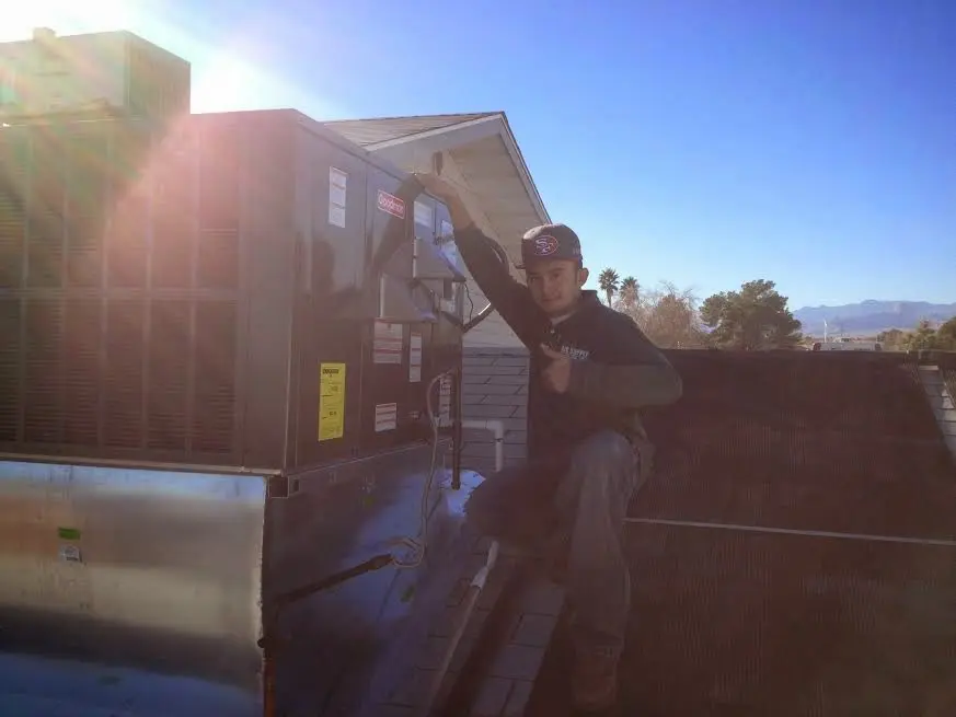 HVAC technician performing HVAC Inspection on a rooftop unit in Byron